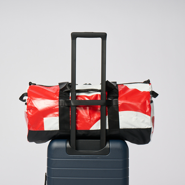 Best beach bag for travel resting on a rolling suitcase handle