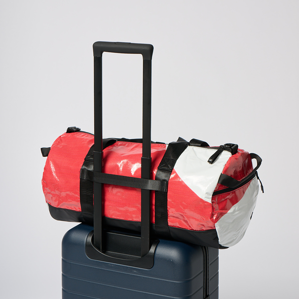 Best beach bag for travel resting on a rolling suitcase handle